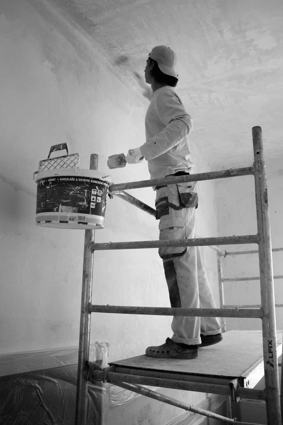 Painter preparing an interior wall from scaffolding